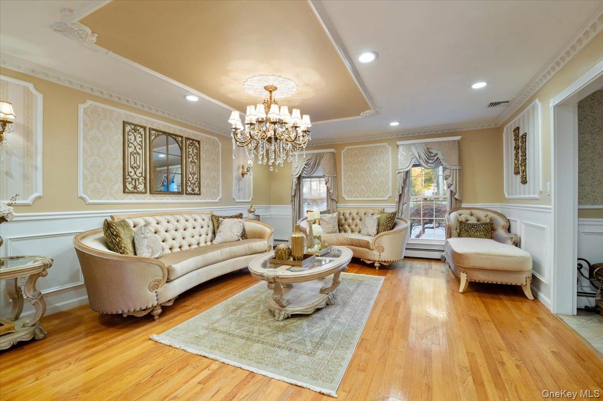 626 Caledonia Road Dix Hills, NY 11746 - Photo 7 of 50 Living area with a raised ceiling, a decorative wall, crown molding, wainscoting, and recessed lighting