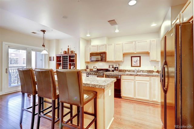 a kitchen with stainless steel appliances granite countertop a dining table chairs refrigerator and sink