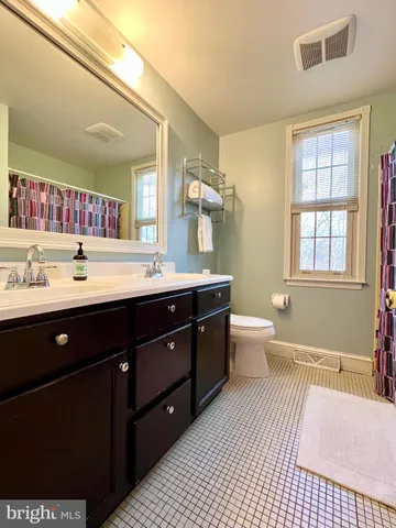 a spacious bathroom with a double vanity sink a mirror and a toilet