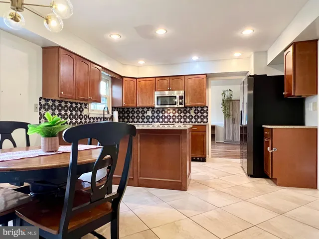 a kitchen with stainless steel appliances granite countertop a refrigerator a stove a sink a dining table and chairs