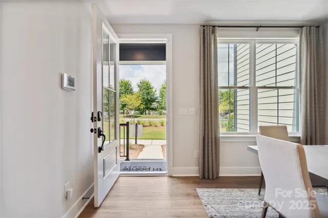a view of a hallway with wooden floor and a livingroom with glass door