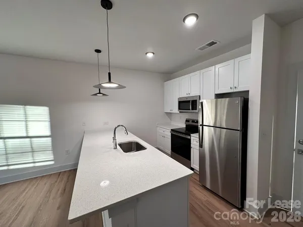 a kitchen with kitchen island a counter space a sink appliances and cabinets