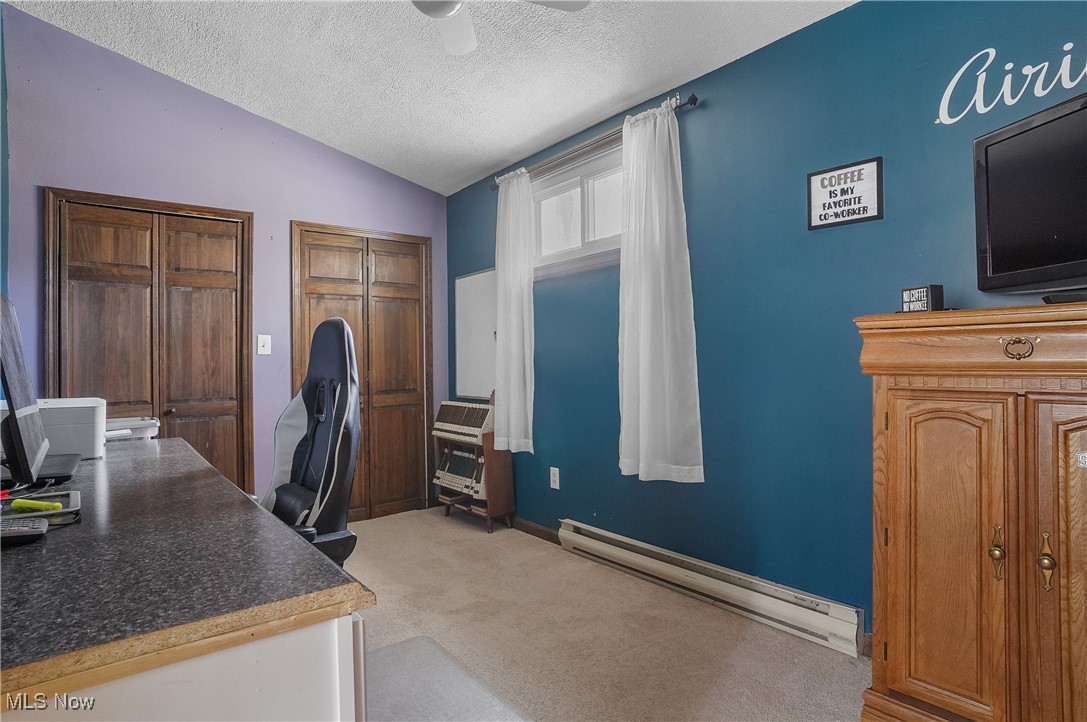 35977 Teegarden Road Salem, OH 44460 - Photo 31 of 50 Home office with vaulted ceiling, a textured ceiling, ceiling fan, a baseboard radiator, and light carpet