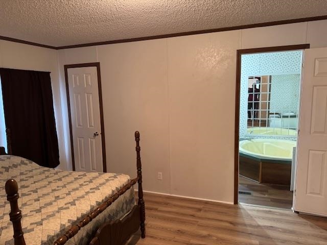 367 Eldie Foster Road Pocahontas, TN 38061 - Photo 9 of 14 Bedroom with ornamental molding, connected bathroom, light wood-style floors, and a textured ceiling