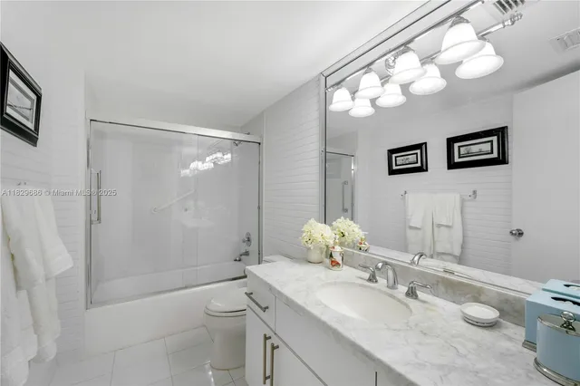 a bathroom with a granite countertop sink mirror vanity and toilet