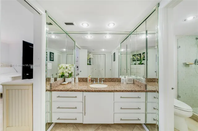 a bathroom with a granite countertop sink mirror vanity and toilet