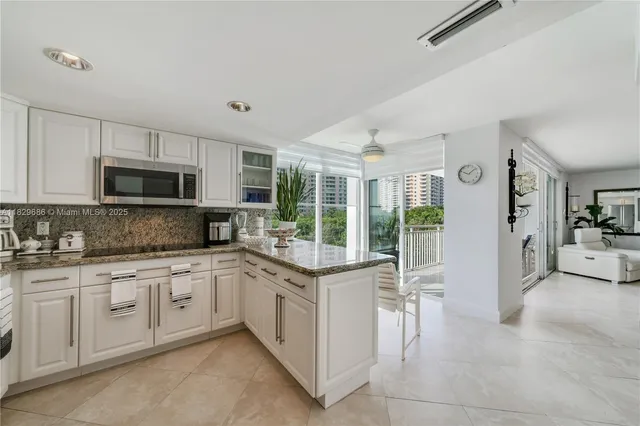 a open kitchen with granite countertop a sink and white cabinets