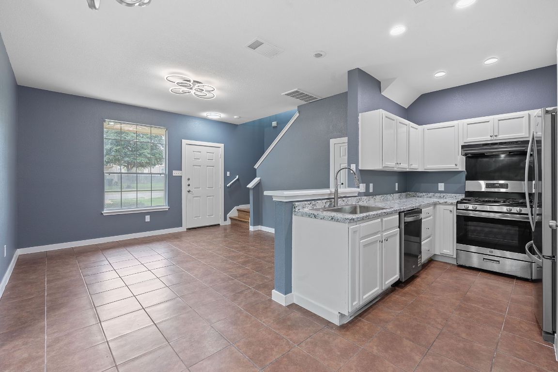 14517 Harris Ridge Boulevard, Unit B Pflugerville, TX 78660 - Photo 11 of 26 a kitchen with granite countertop a stove sink and microwave