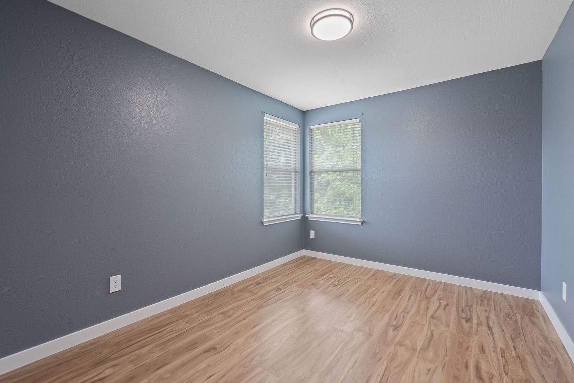 14517 Harris Ridge Boulevard, Unit B Pflugerville, TX 78660 - Photo 19 of 26 an empty room with wooden floor and windows