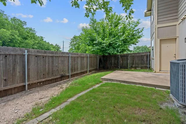 a view of a backyard with large trees and wooden fence