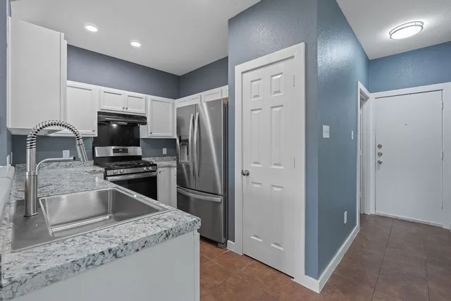 a kitchen with granite countertop a refrigerator and a sink