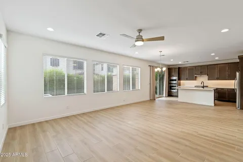 a view of an empty room with kitchen and a window