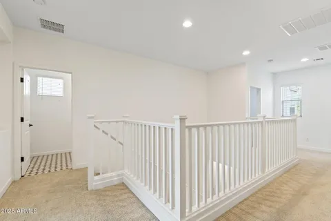 an empty room with chandelier fan and windows