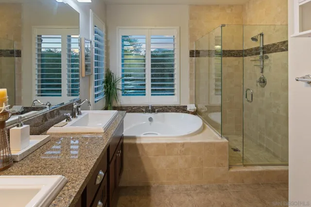 a bathroom with a granite countertop sink a mirror and a bathtub