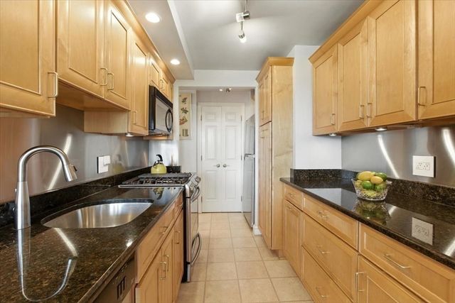 a kitchen with granite countertop a sink a stove and cabinets