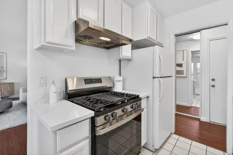 a kitchen with stainless steel appliances granite countertop a stove a refrigerator and a white cabinets