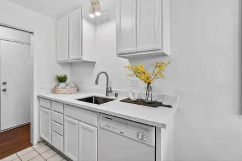 a kitchen with white cabinets a sink and dishwasher