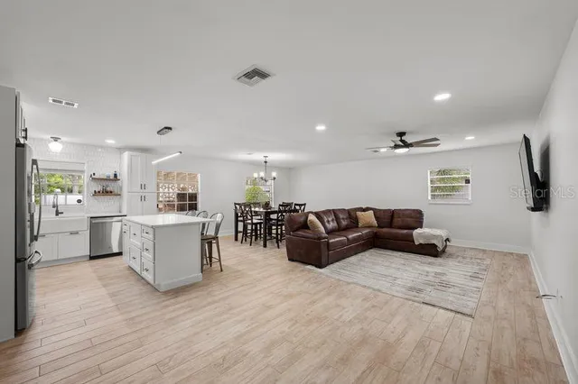 a large kitchen with kitchen island a dining table chairs stainless steel appliances and cabinets