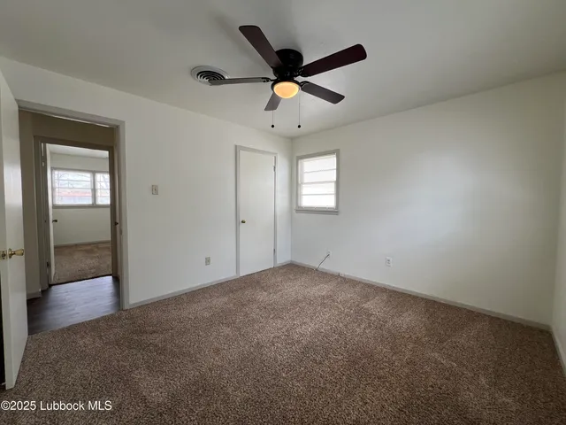 an empty room with windows and ceiling fan