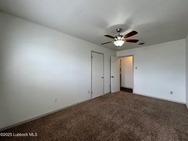 an empty room with ceiling fan and window