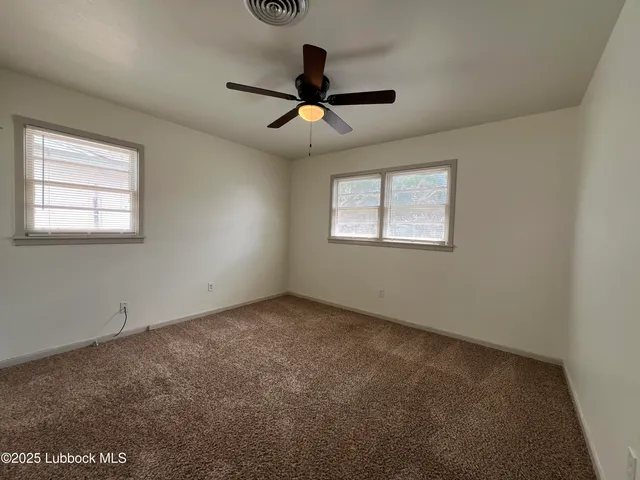 en empty room with windows and ceiling fan