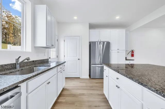 a kitchen with granite countertop a sink and refrigerator