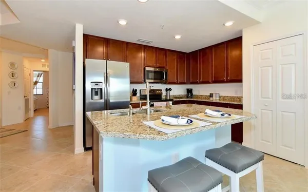 a kitchen with kitchen island a stove a sink a refrigerator and chairs
