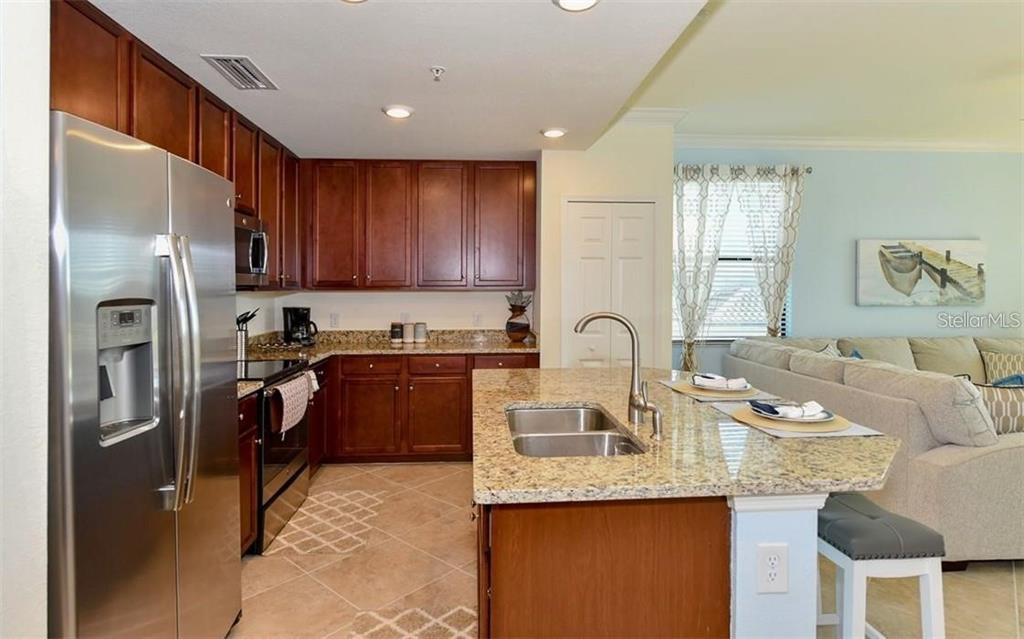 16904 Vardon Terrace, Unit 201 Lakewood Ranch, FL 34211 - Photo 12 of 35 a kitchen with stainless steel appliances granite countertop a refrigerator sink and cabinets