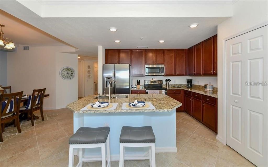 16904 Vardon Terrace, Unit 201 Lakewood Ranch, FL 34211 - Photo 13 of 35 a kitchen with a dining table chairs and refrigerator
