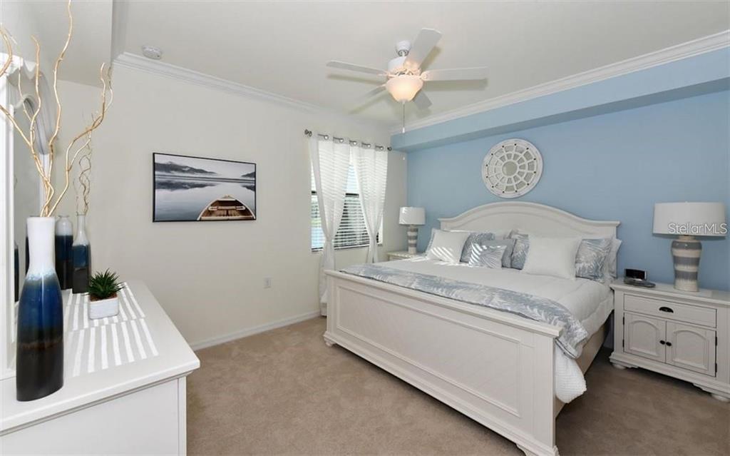 16904 Vardon Terrace, Unit 201 Lakewood Ranch, FL 34211 - Photo 15 of 35 a bedroom with a bed and a chandelier