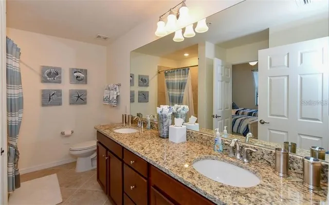 a bathroom with a granite countertop double vanity sink mirror and toilet