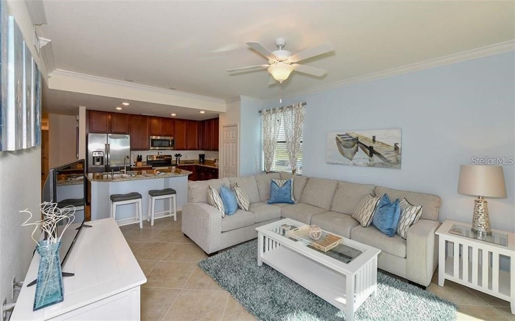 16904 Vardon Terrace, Unit 201 Lakewood Ranch, FL 34211 - Photo 6 of 35 a living room with furniture a kitchen view and a chandelier