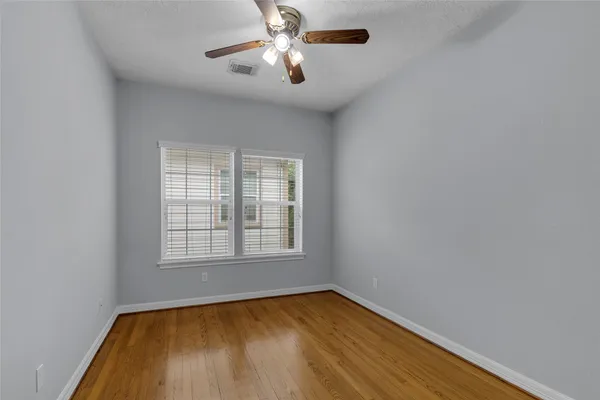 an empty room with chandelier fan and windows
