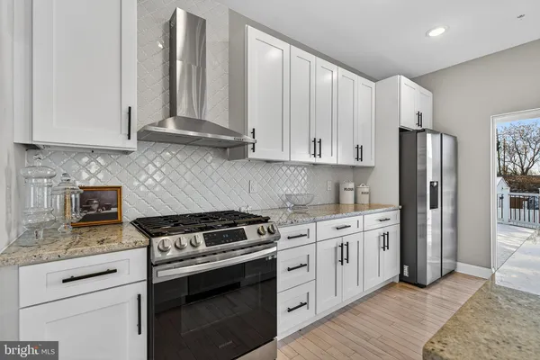 a kitchen with stainless steel appliances granite countertop a stove a refrigerator and a white cabinets