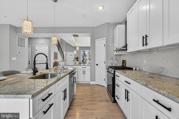 a kitchen with granite countertop a sink and white cabinets