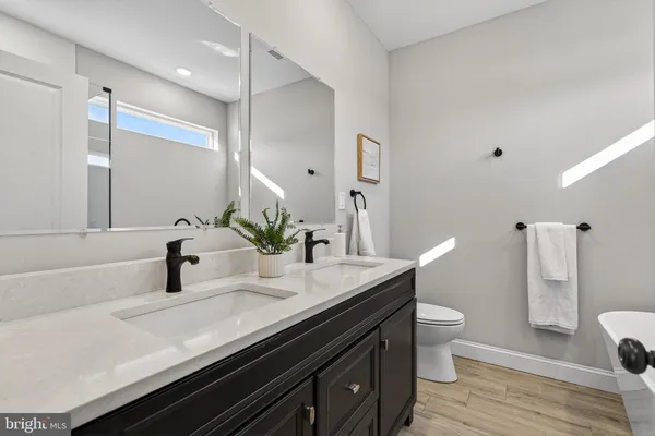 a bathroom with a granite countertop sink a toilet and a large mirror