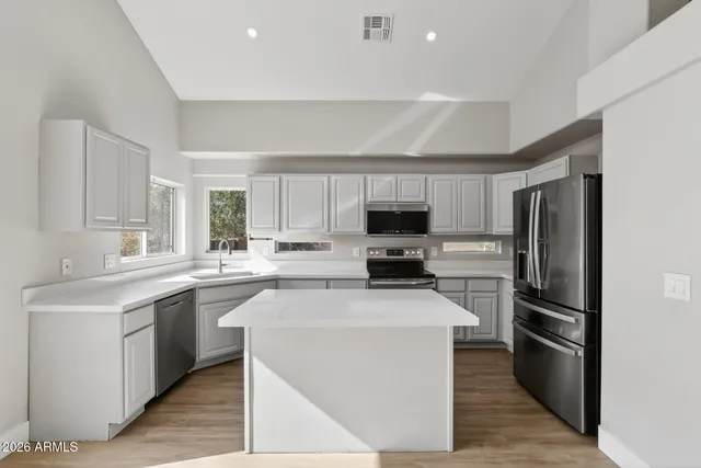 a kitchen with stainless steel appliances a white cabinets wooden floor and a sink