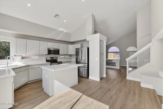 a kitchen with stainless steel appliances granite countertop a stove a sink dishwasher and a microwave oven with white cabinets