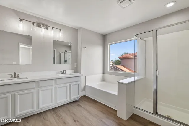 a spacious bathroom with double vanity a mirror and a bathtub