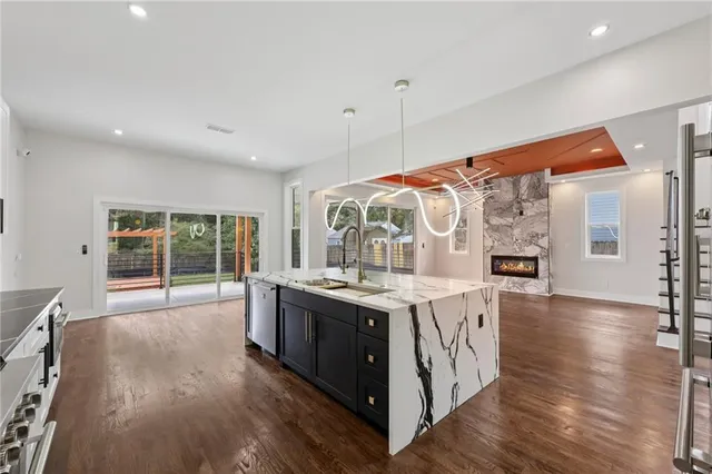 a large kitchen with stainless steel appliances granite countertop a stove and a wooden floors