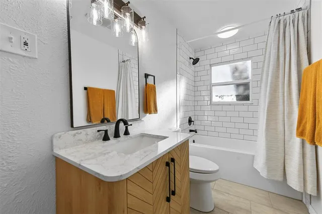 a bathroom with a granite countertop sink toilet a mirror a vanity and shower