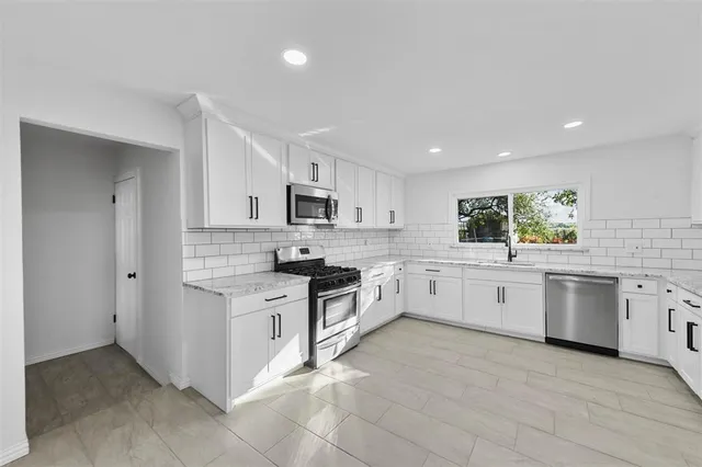 a large kitchen with stainless steel appliances granite countertop a stove a sink dishwasher and a refrigerator