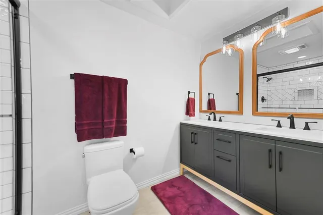 a bathroom with a toilet sink vanity granite and mirror