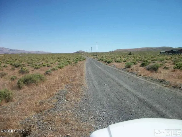 a view of a dry yard with wooden fence