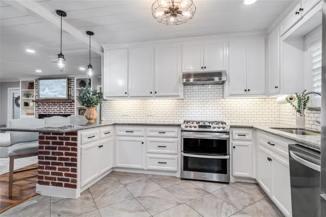 a kitchen with granite countertop stainless steel appliances a sink a stove and cabinets