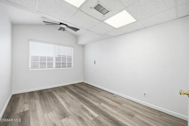 an empty room with wooden floor fan and windows