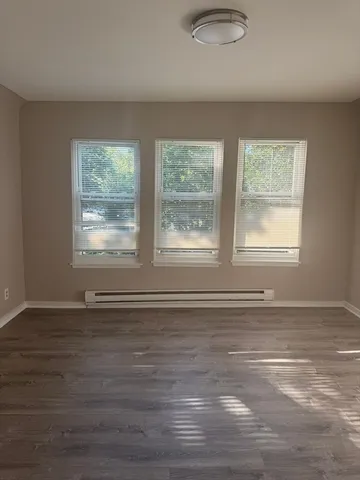 a view of an empty room with wooden floor and a window