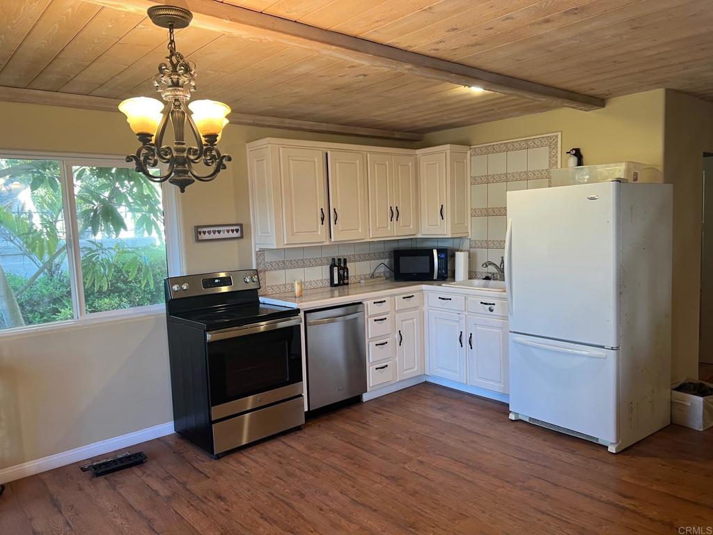 9450 La Jolla Farms Road La Jolla, CA 92037 - Photo 27 of 29 a kitchen with stainless steel appliances granite countertop a refrigerator a sink dishwasher a stove and white countertops with wooden floor