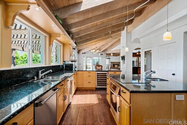 a kitchen with stainless steel appliances granite countertop a sink a stove and a wooden floors
