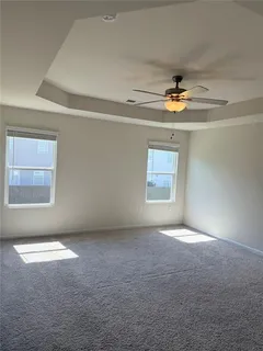 an empty room with windows and chandelier fan